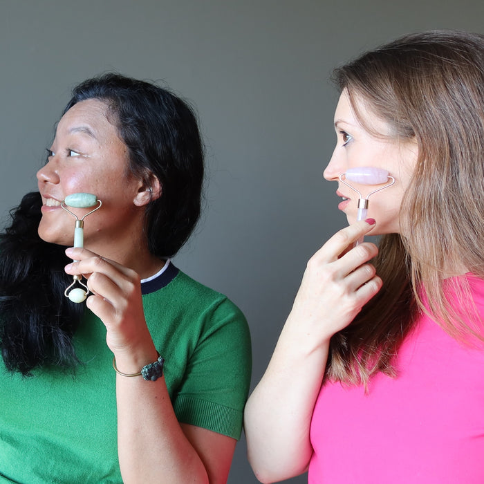 jessica of satin crystals using a jade roller on her cheek and holly using a rose quartz roller on hers